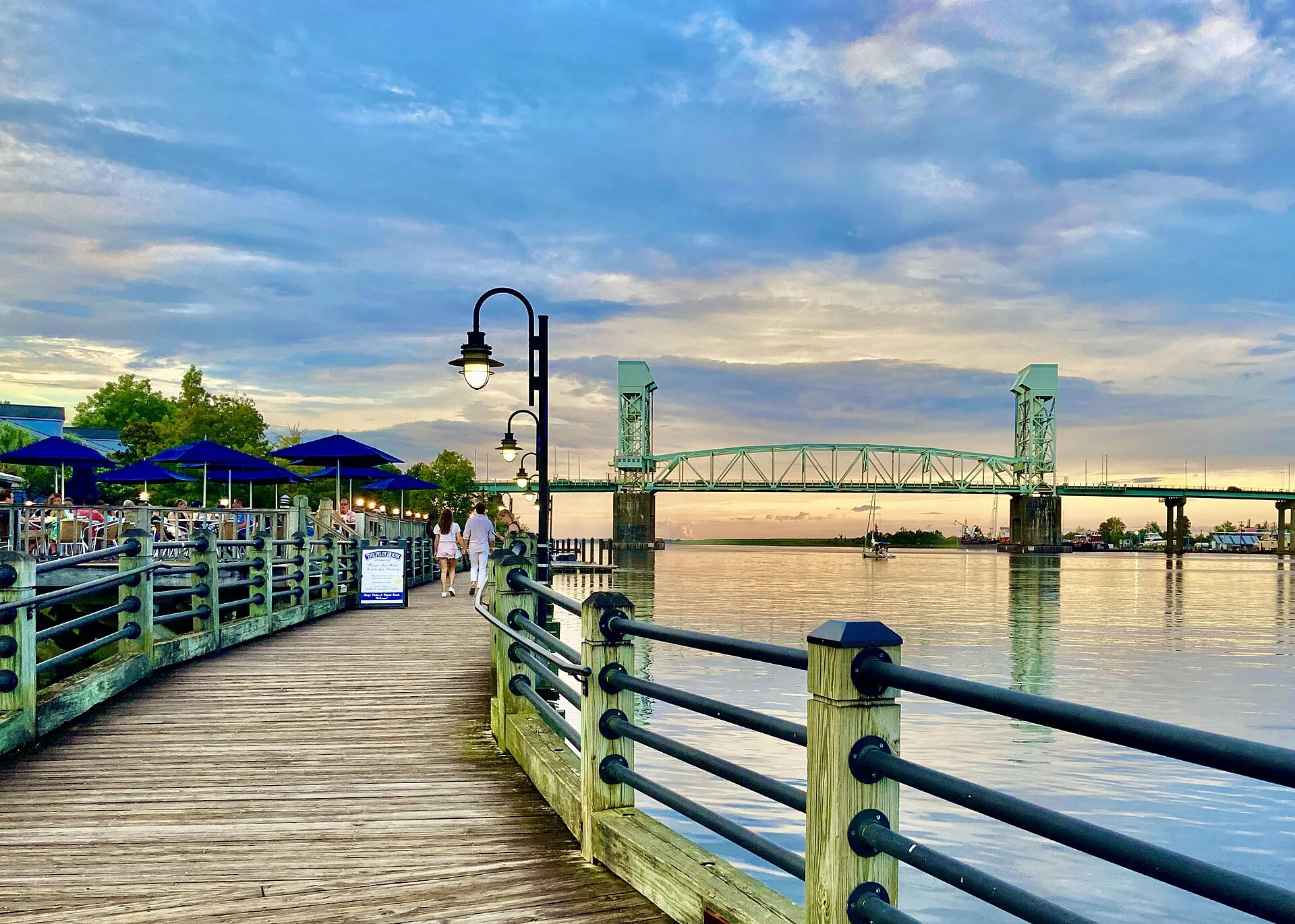 The Riverwalk along the Cape Fear River in downtown Wilmington, North Carolina, with the Cape Fear Memorial Bridge at sunset